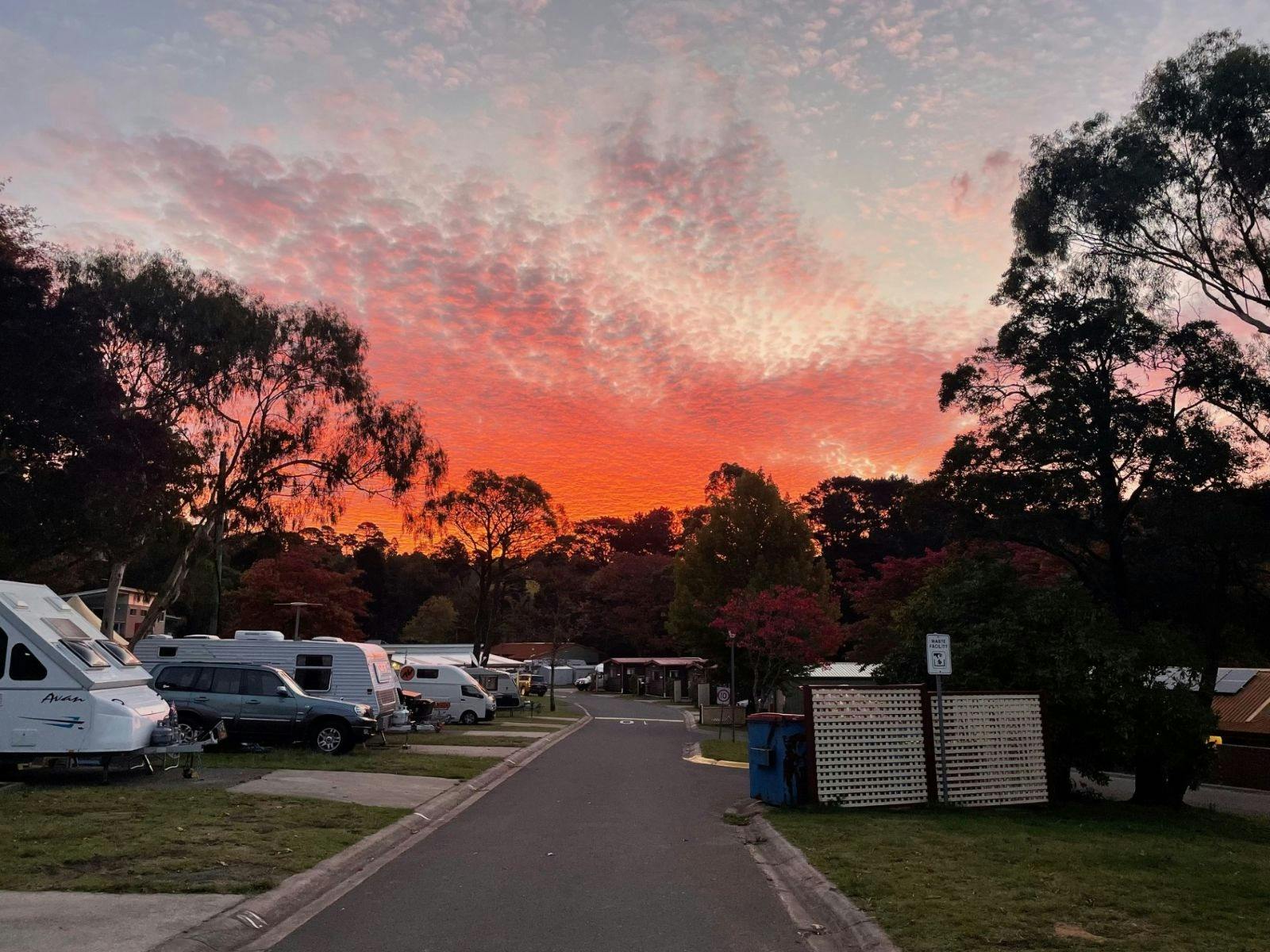 Several caravans parked in a line with a red sunset in the background